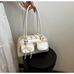 Détail du sac bandoulière en cuir blanc cassé avec pendentif nœud perlé et doubles poches