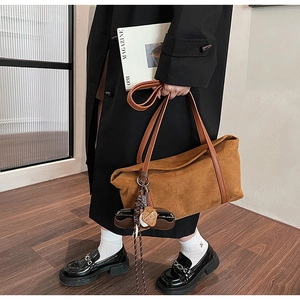 Close-up of caramel suede tote bag with leather straps and bear tassel charm