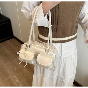Chic cream white Boston bag with pearl bow charm shown on model in a casual outfit