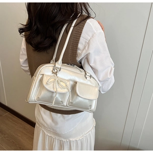 Détail du sac Boston blanc perle avec un nœud élégant et des poches à rabat avant