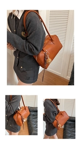 Detail of vintage brown Boston shoulder bag featuring woven lanyard and plush charm
