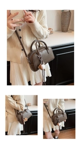 Macro detail of dark brown hobo shoulder bag with baseball charm and top handle