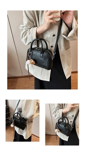 Detail view of black lychee leather Boston bag featuring baseball glove charm and silver hardware