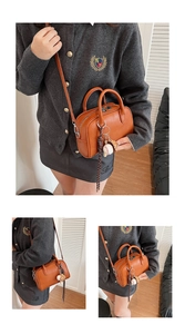 Detail view of brown leather boston bag with baseball charm and silver zipper
