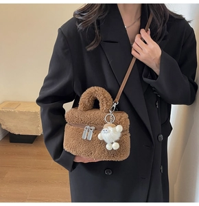Gros plan d'un sac seau en peluche marron avec un charme d'agneau et des zips en métal