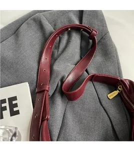 Detail of adjustable wine red leather shoulder strap with gold-tone metal zipper hardware