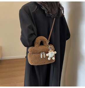Détail du sac seau en peluche marron avec bandoulière en cuir et charm blanc décoratif