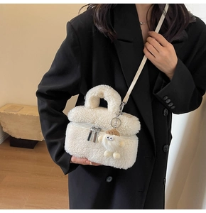 Détail d'un sac seau en peluche blanche avec breloque porté par un mannequin femme