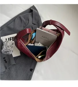 Close-up of burgundy leather dumpling bag interior showing spacious capacity on gray blazer