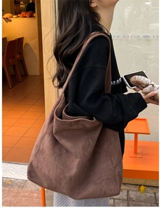 Brown suede tote bag shown on shoulder in a warm cafe setting for daily styling