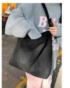 Side view of large black suede tote bag with wide strap on a model for daily commute