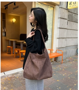 Close-up of brown suede tote bag with wide strap in a modern cafe setting