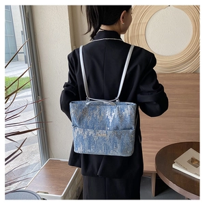 Modern denim backpack with silver texture and metallic plate shown on model