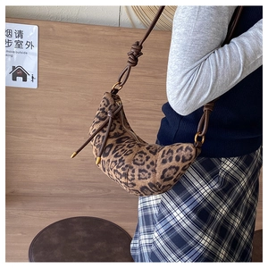 Dettaglio della borsa a mezzaluna in camoscio leopardato indossata da una modella