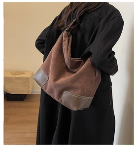 Detail of brown suede tote bag with white contrast stitching and smooth leather patches