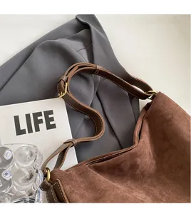 Detail of adjustable dark brown leather shoulder strap on a brown suede tote bag