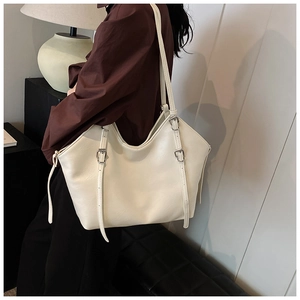 Detail of cream leather tote bag with long buckled straps shown on a female model