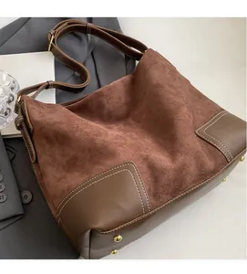 Macro detail of brown suede and smooth leather stitching with gold rivets on tote bag