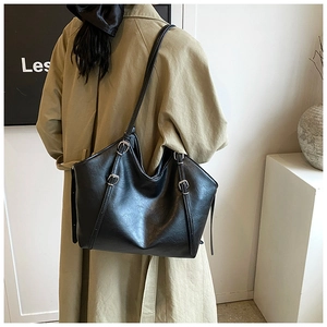Detail of minimalist black PU leather tote bag featuring adjustable metal buckles