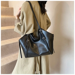 Detail of black large-capacity tote bag with silver buckle on premium faux leather