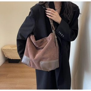 Close-up of brown suede tote bag with contrast stitching on leather straps and corners