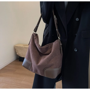 Detail view of large brown suede hobo bag featuring contrast stitching and leather base
