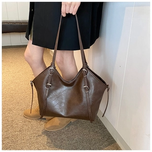 Detailed view of dark brown vintage tote bag featuring polished leather and metal buckles