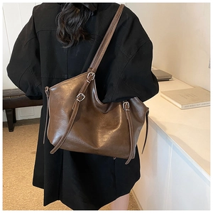 Detail of adjustable silver buckle and premium leather texture on brown tote bag