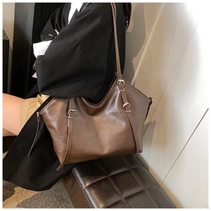 Detail view of vintage brown PU leather tote bag with silver metal buckles on a model