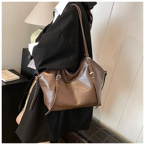 Close-up of a large vintage brown leather tote bag with metallic buckle and slim strap