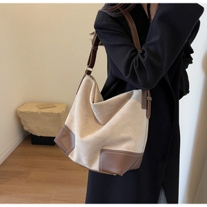 Close-up of hobo tote bag featuring beige suede canvas and brown leather stitching details