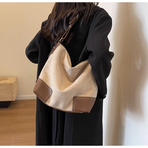 Detail of large beige tote bag with brown leather corners and contrast stitching