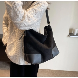 Detail of black suede hobo bag with contrast stitching and adjustable shoulder strap