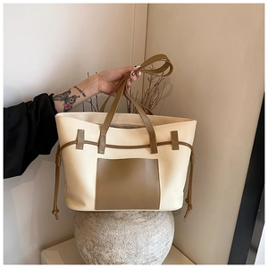 Detailaufnahme einer Canvas-Tragetasche mit brauner Ledertasche und Griffen auf Stein