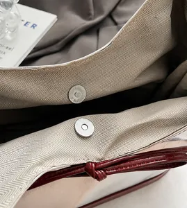 Detail of silver magnetic closure with herringbone lining and burgundy leather trim