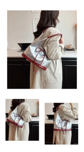 Close-up of a silver PU tote bag with red bow detail and contrast piping handles