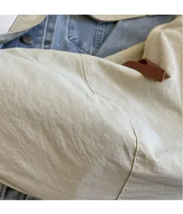 Close-up of beige lightweight nylon fabric with pleated texture and leather zipper puller
