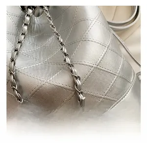 Macro shot of silver quilted bucket bag with leather-interwoven chain strap details