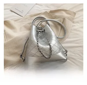 Detailed view of silver quilted bucket bag with chain drawstring on soft fabric