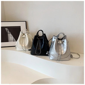 Three quilted bucket bags in white, black and silver on a minimalist display stand
