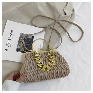 Bovenaanzicht van beige plooitas met grove gouden ketting en retro metalen sluiting
