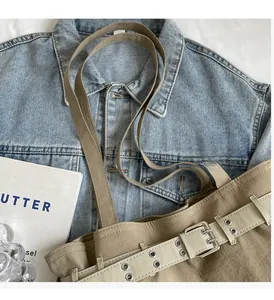 Detail view of khaki nylon tote bag with decorative buckle belt on denim background