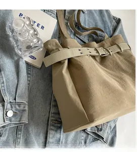 Detail of khaki canvas tote bag showing soft glossy fabric and leather strap closure