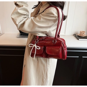 Détail du sac à épaule en cuir verni rouge foncé avec pendentif perle en forme de nœud
