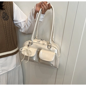 Detail of cream white patent leather shoulder bag with decorative pearl bow charm
