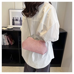 Detailed view of pink rhinestone shell clutch bag with silver chain strap shown with model