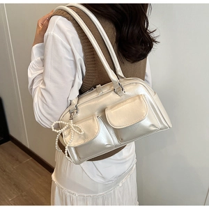 Detail view of cream shoulder bag with pearl bow pendant and double front flap pockets