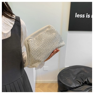 Detail of a sparkling rhinestone shell clutch bag held by a model in a modern interior