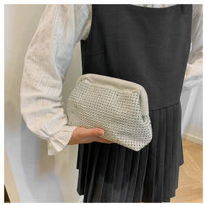 Detail of luxury rhinestone shell bag held by hand, showing premium suede texture