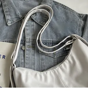 Detailweergave van een witte halve maan schoudertas met verstelbare riem en zilveren hardware